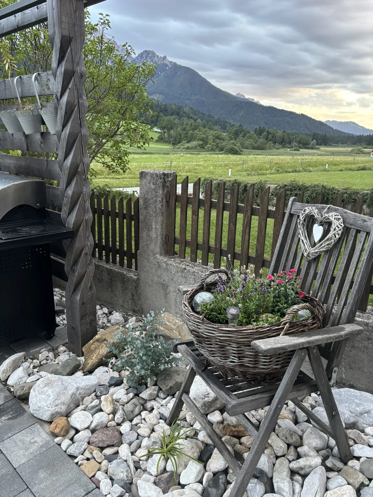 Kotiček na vrtu s košaro rož in travnikom za ograjo